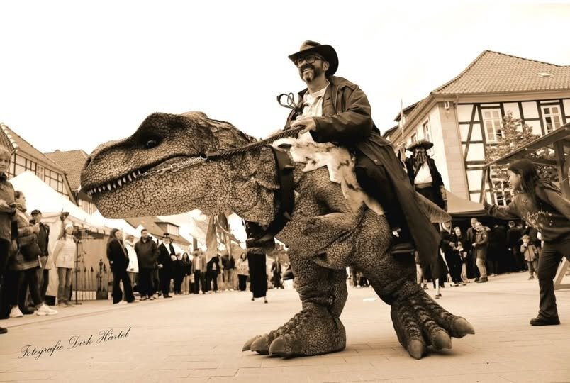 Walker, der Ranger, reitet auf Fred, dem lebensgroßen T-Rex, durch eine Fußgängerzone
